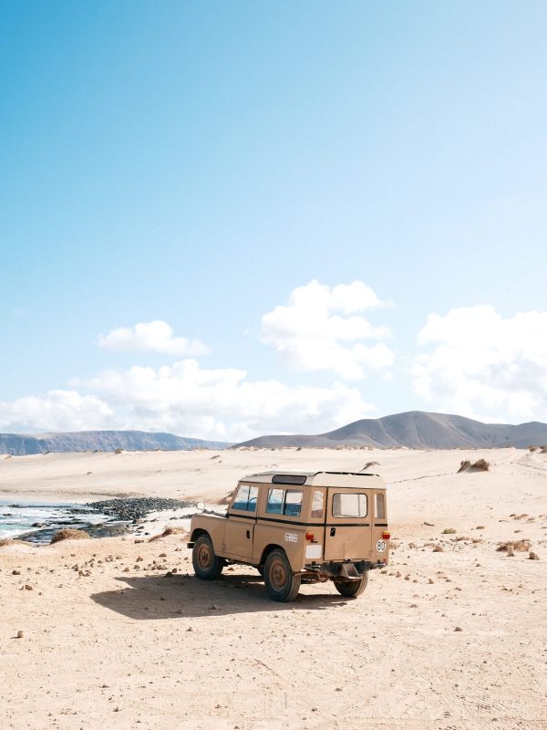 A vertical shot of an off-road car standing in a desert